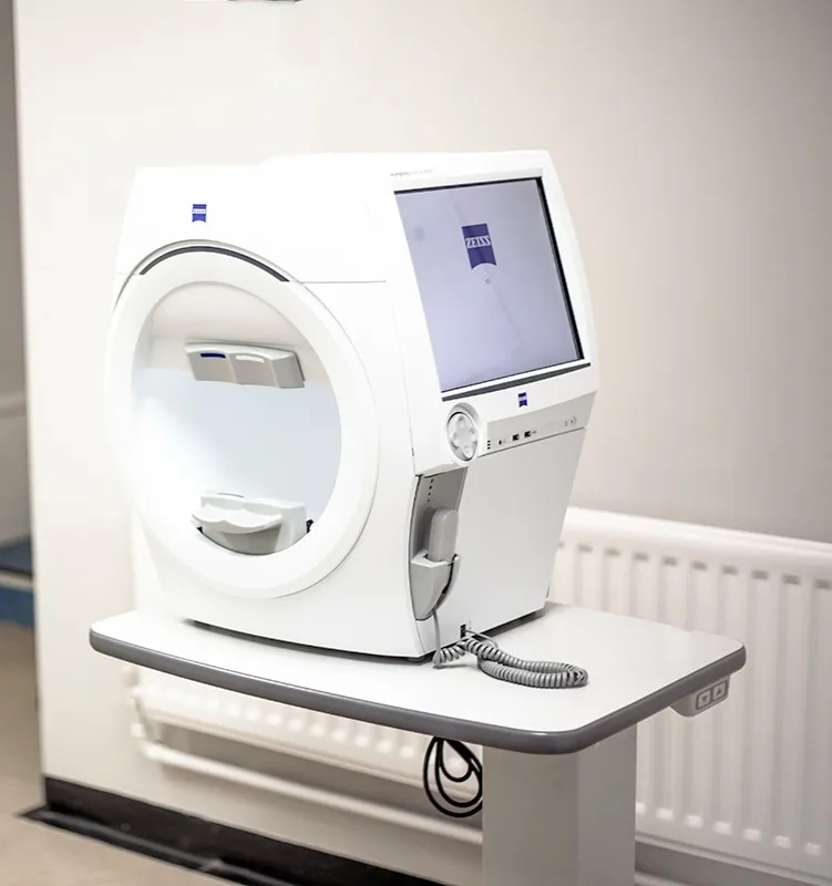 Zeiss eye examination machine with a display screen on a white table in a clinical setting.