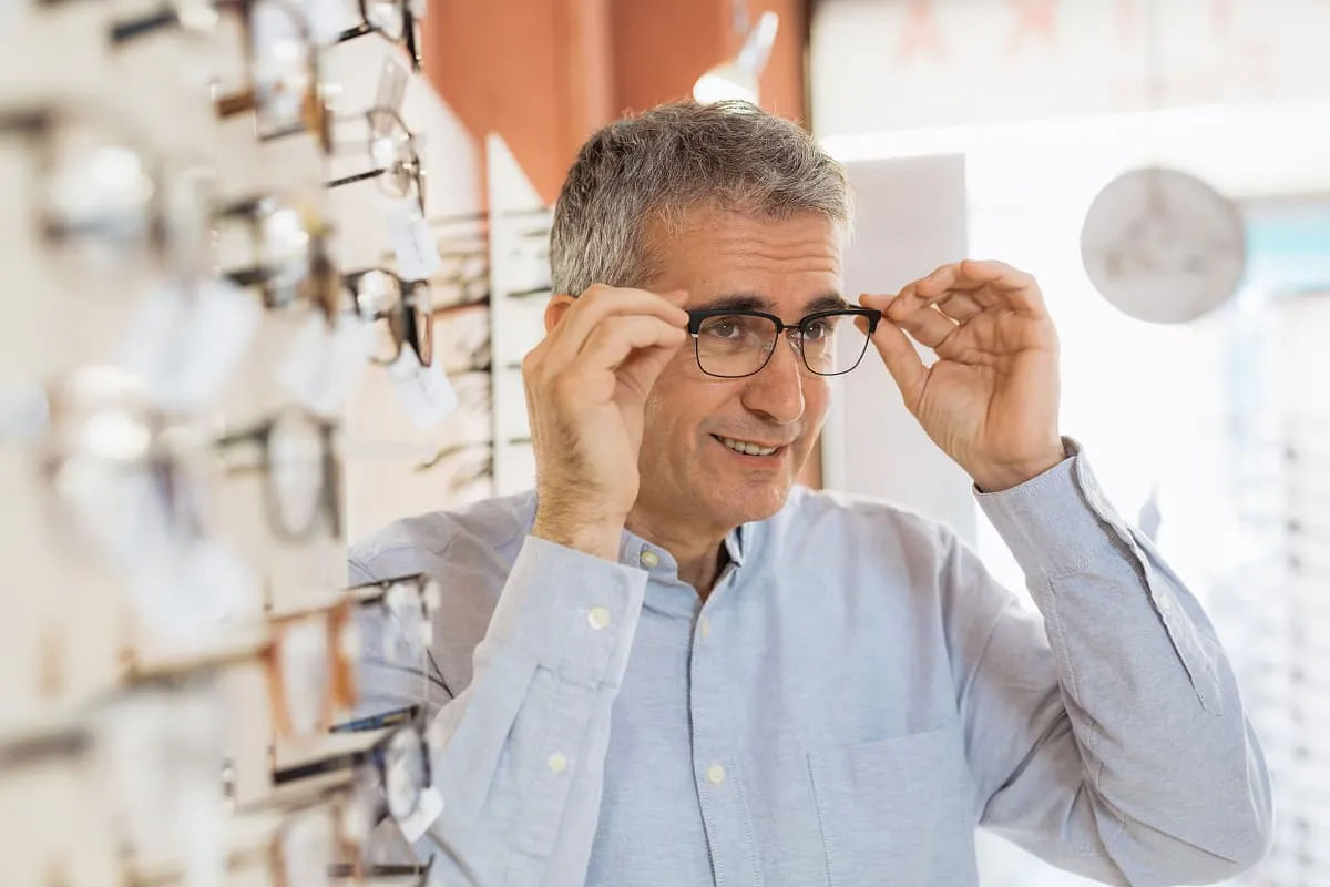 Middle-aged man trying on a pair of eyeglasses in an eyewear store.
