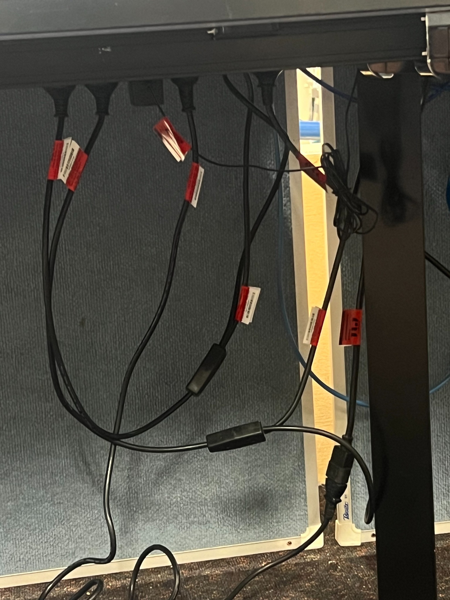 Tagged equipment leads beneath a workstation.
