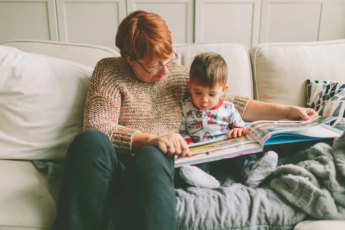 toddler reading at home to grandmother