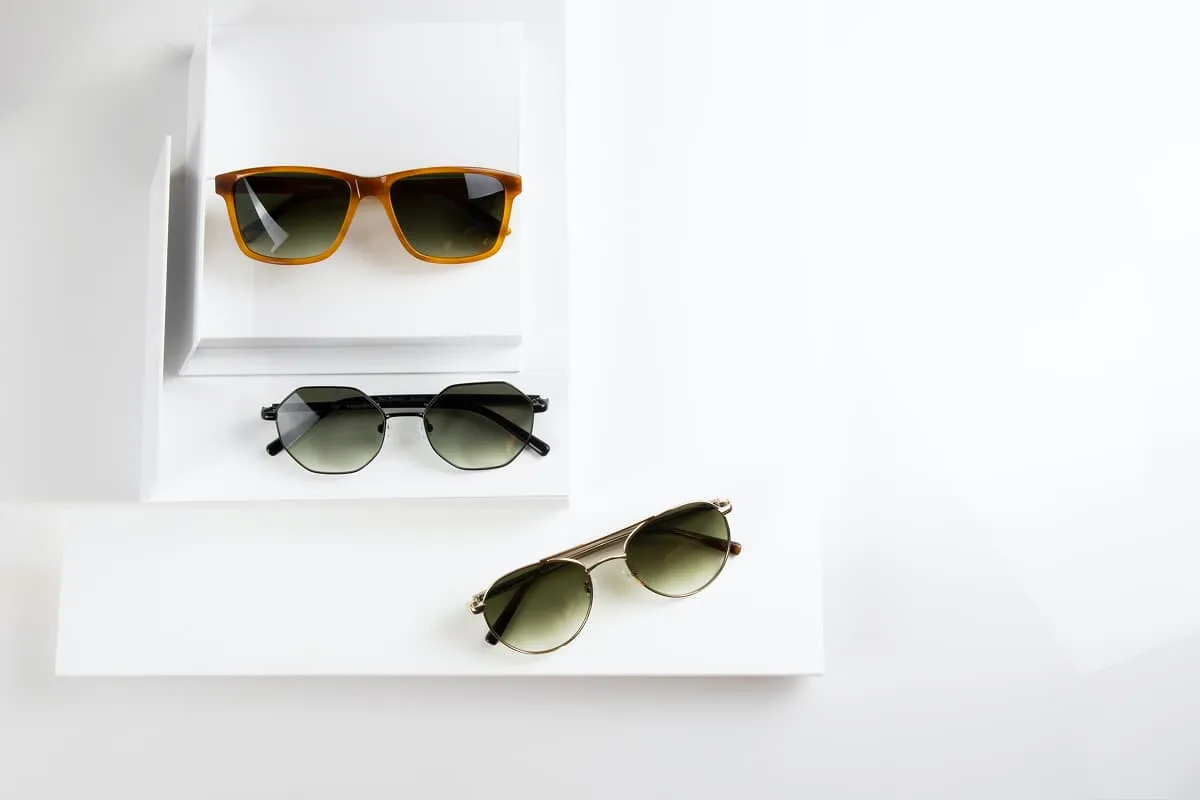Three pairs of sunglasses on white platforms with varying frame styles and tinted lenses.