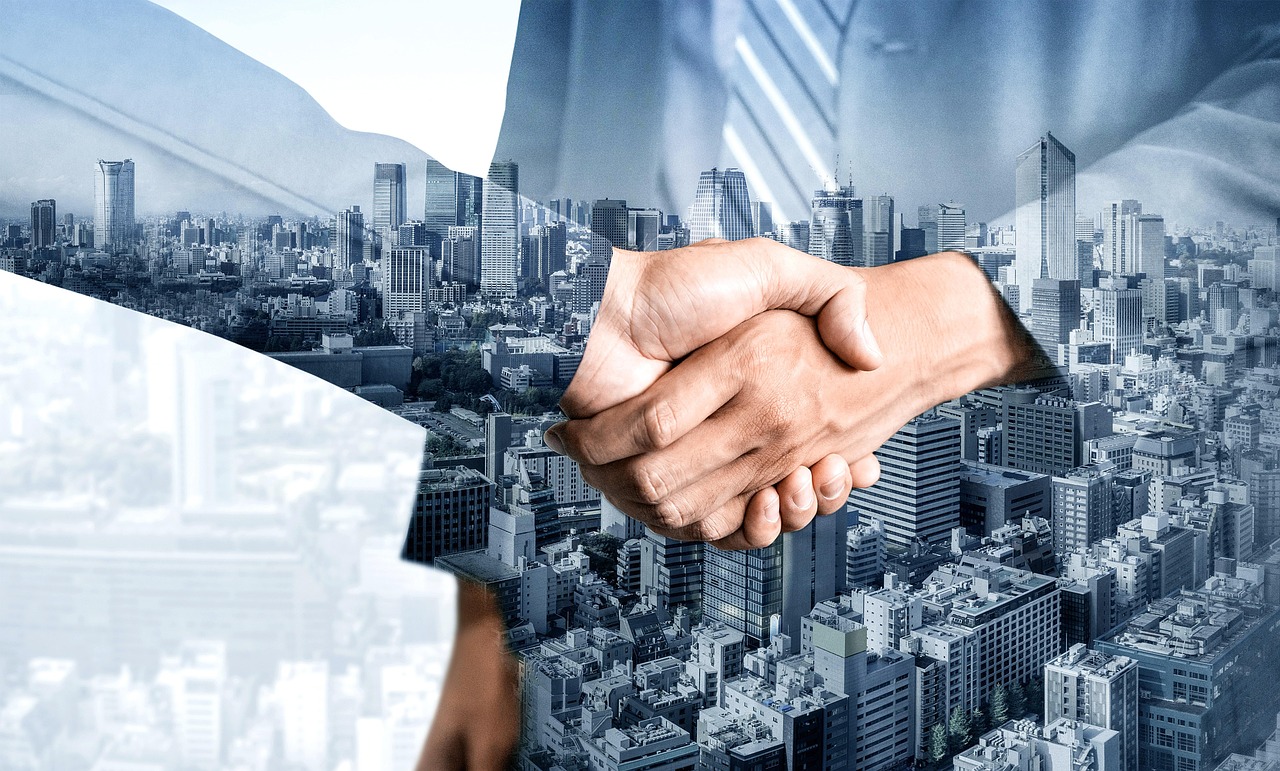 Close-up of a handshake overlaid on a city skyline with tall buildings.