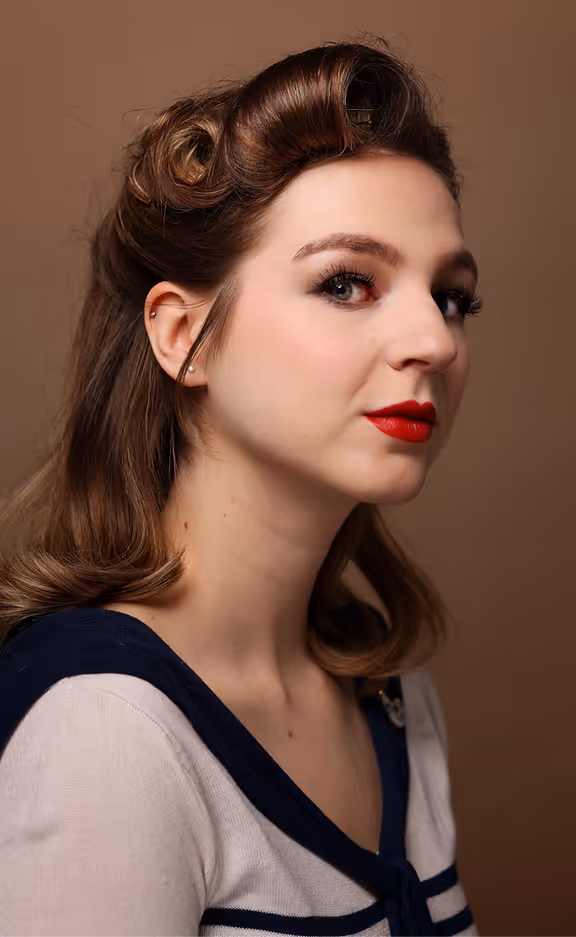 Junge Frau mit Retro-Frisur und rotem Lippenstift vor braunem Hintergrund.