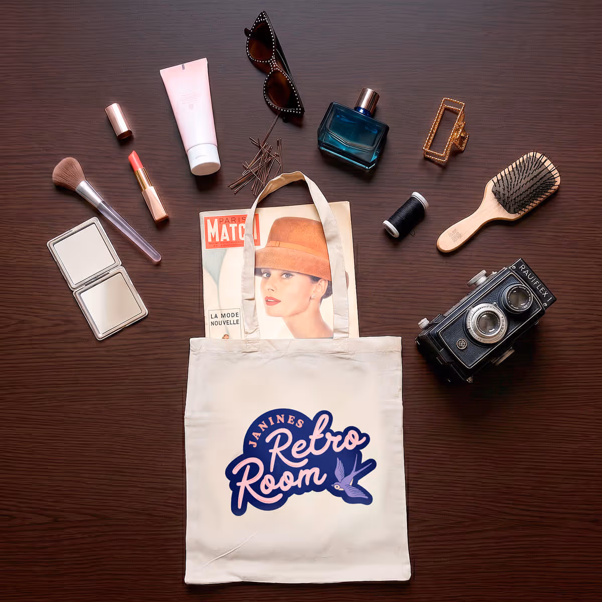 Weiße Tragetasche mit Aufdruck 'Janines Retro Room' auf einem Holztisch, umgeben von Vintage-Kosmetikartikeln, Sonnenbrille, altem Magazin und einer Retro-Kamera.