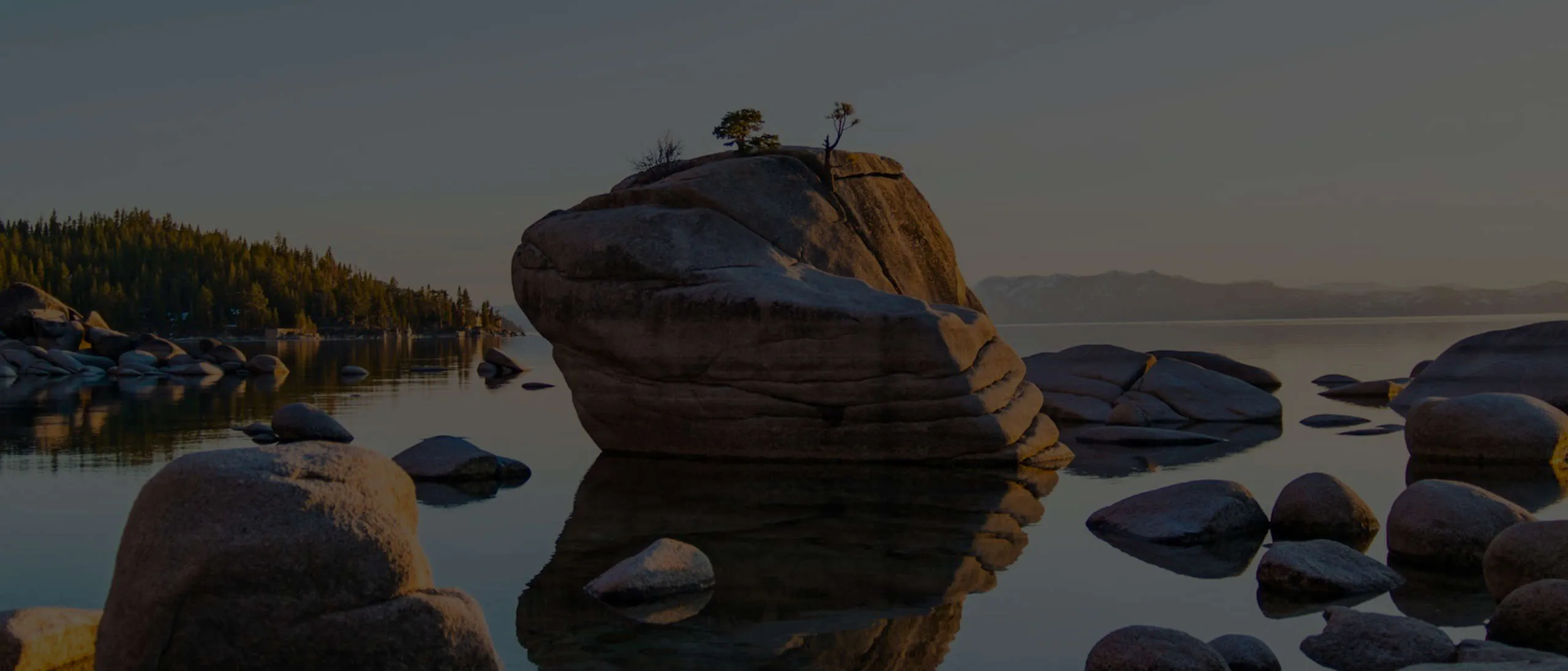 A person standing on a rock in the middle of a lake.