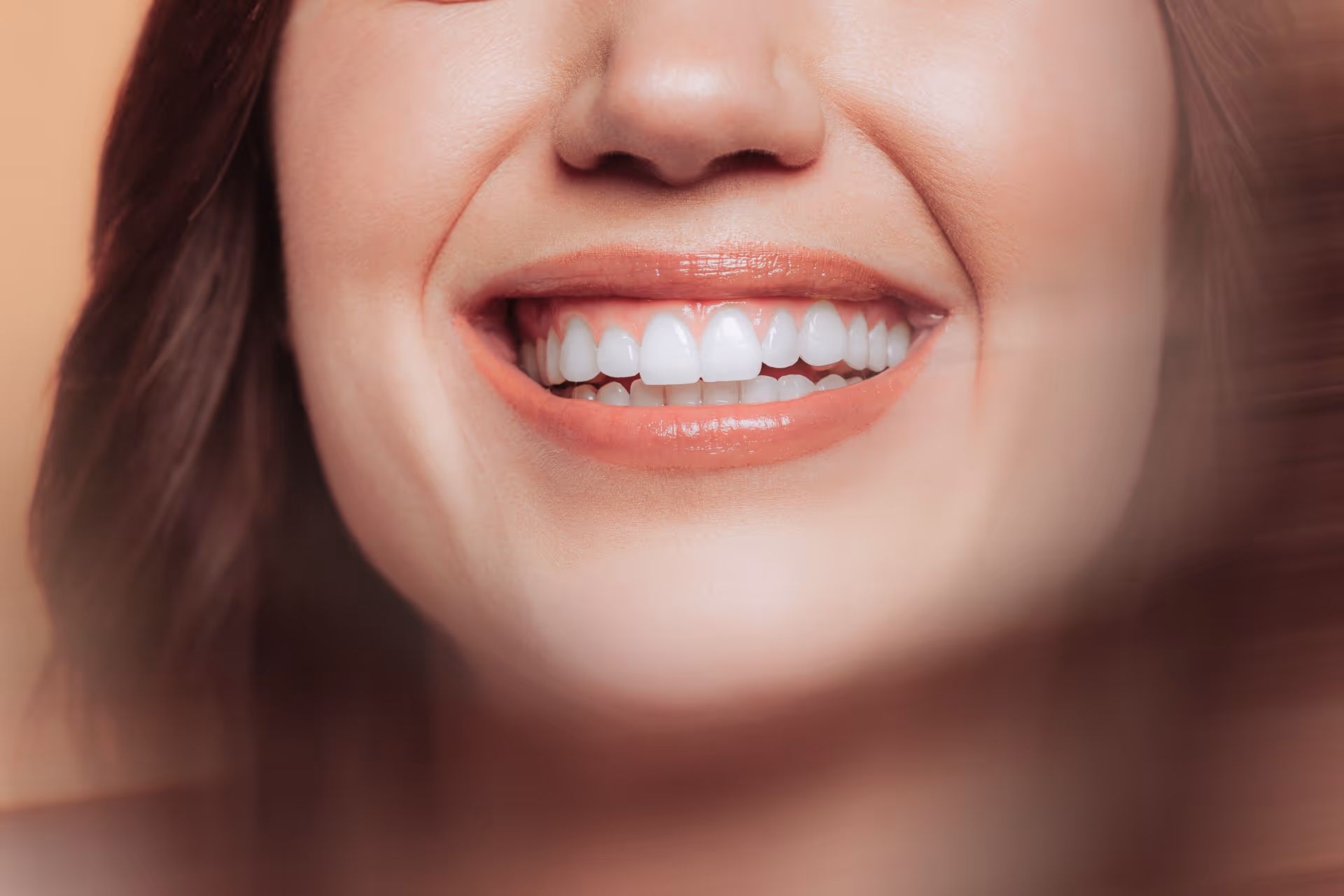 Nahaufnahme vom Lächeln einer Frau mit weißen, gepflegten Zähnen und glänzendem Lippenstift.