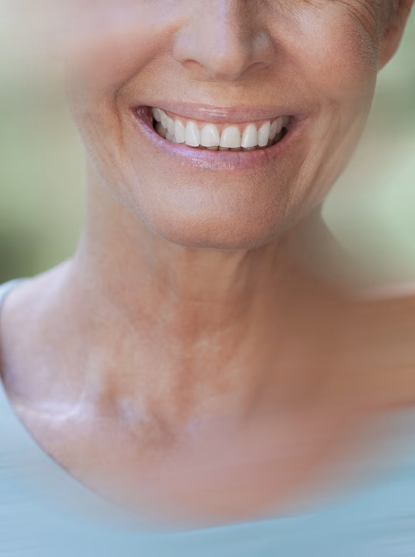 Nahaufnahme eines lächelnden Gesichts mit sichtbaren weißen Zähnen und leicht sichtbaren Altersfalten.