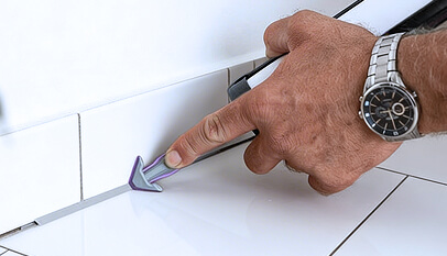 Using a REGGA caulking gun nozzle attachmentto smooth silicone sealant in the corner between tile and wall