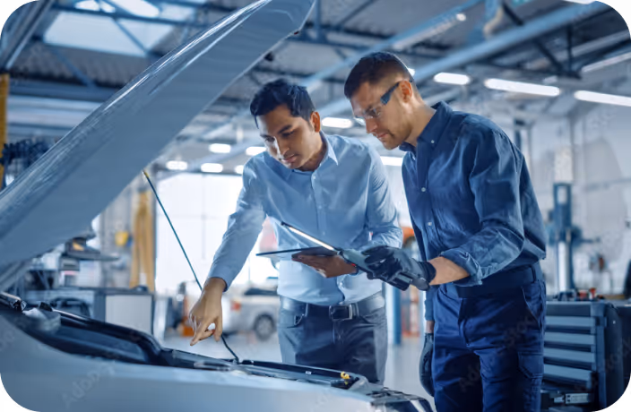 Two men working on a car in a garage.