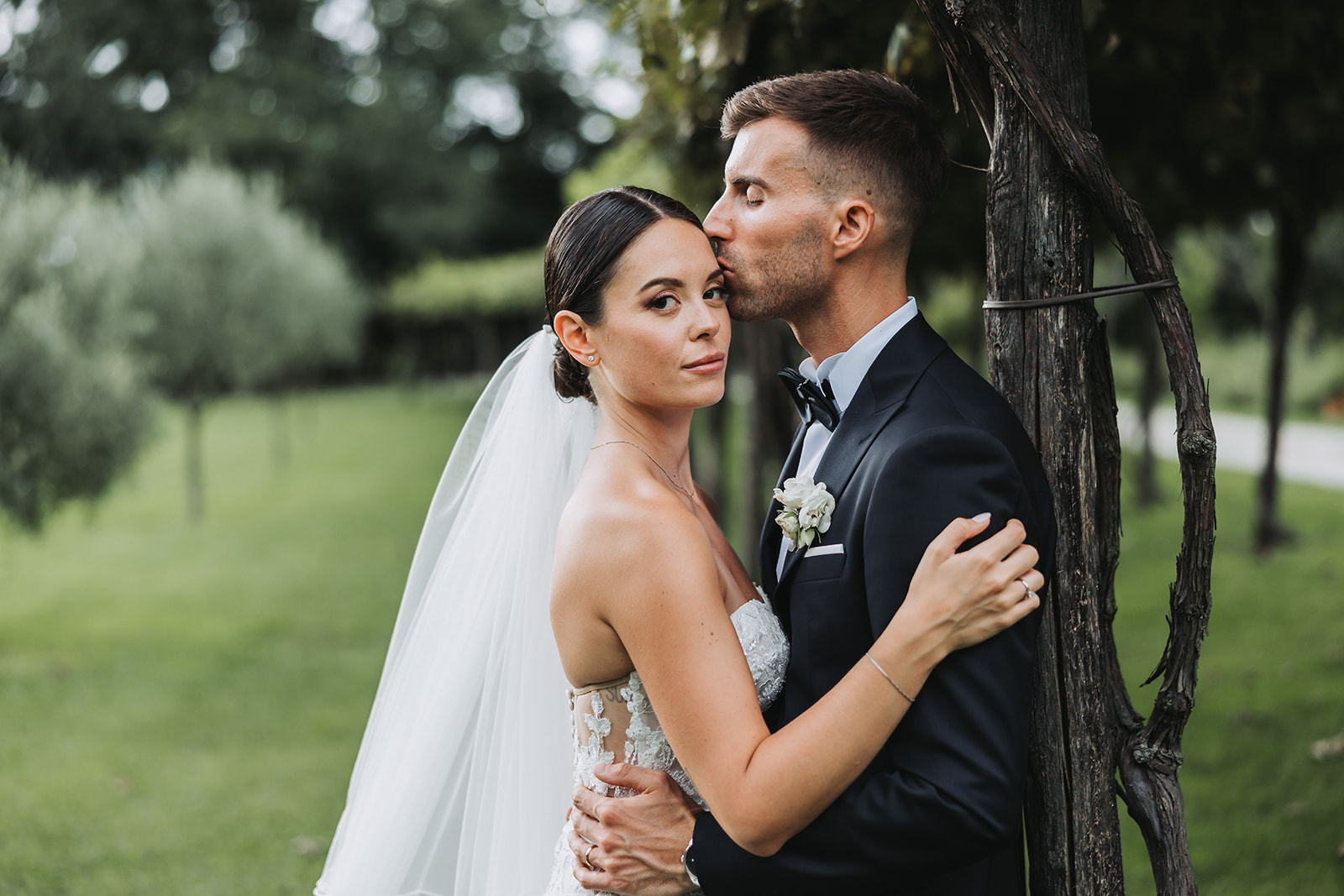 Groom kisses bride beneath the trees at Villa Caprera