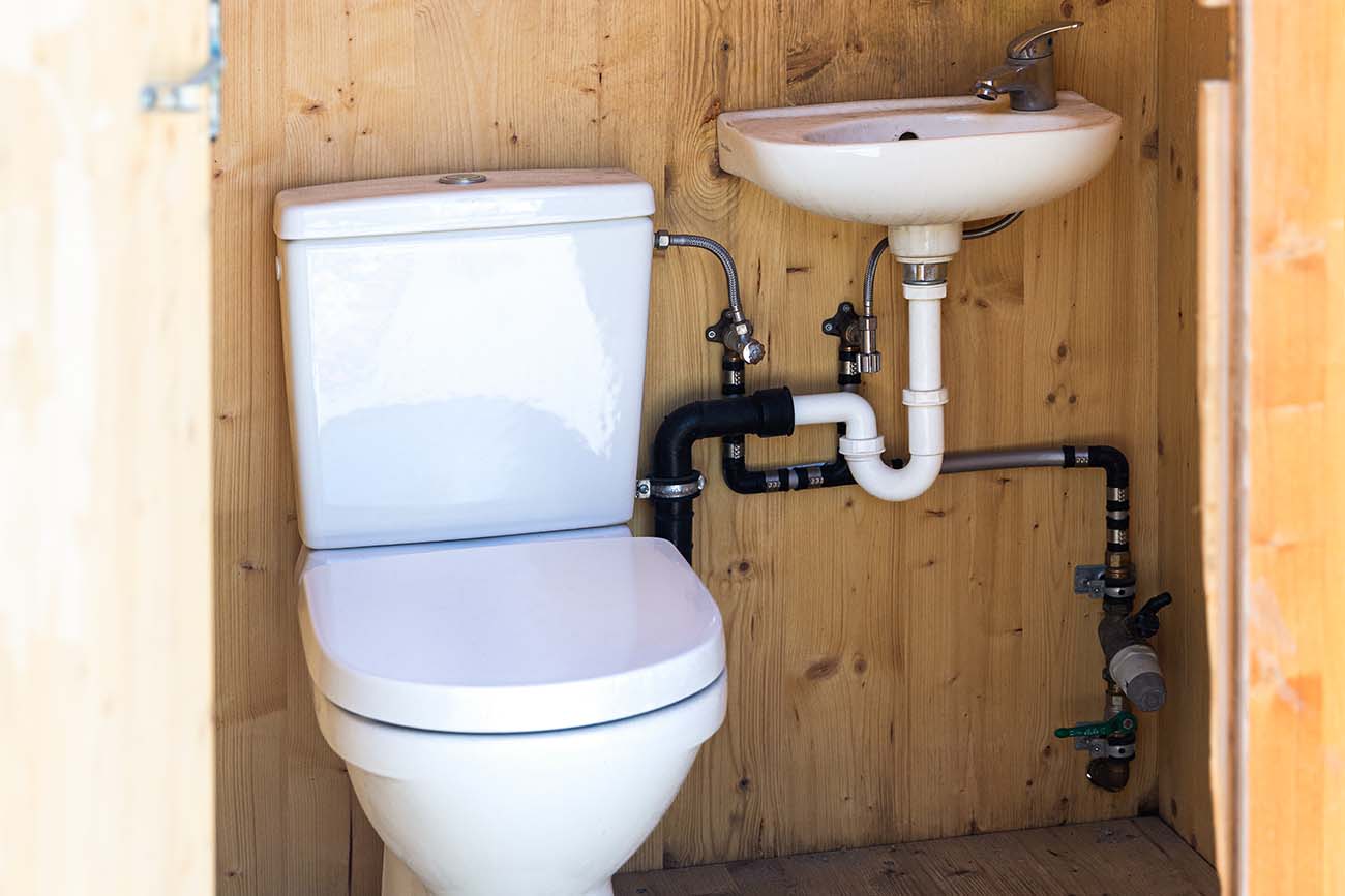 intérieur d'une cabine WC en bois avec un lavabo et des toilettes connectées