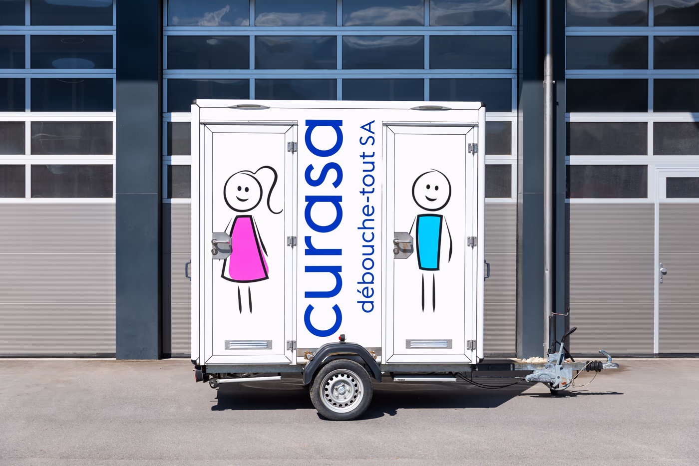 Une petite remorque avec 2 cabines WC, une pour les femmes et l'autre pour les hommes