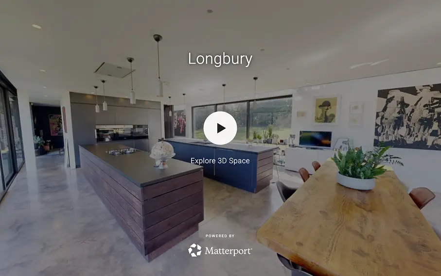 Modern kitchen with a long black dining table, black chairs, dark cabinetry, large windows, and a view of a garden and pool.