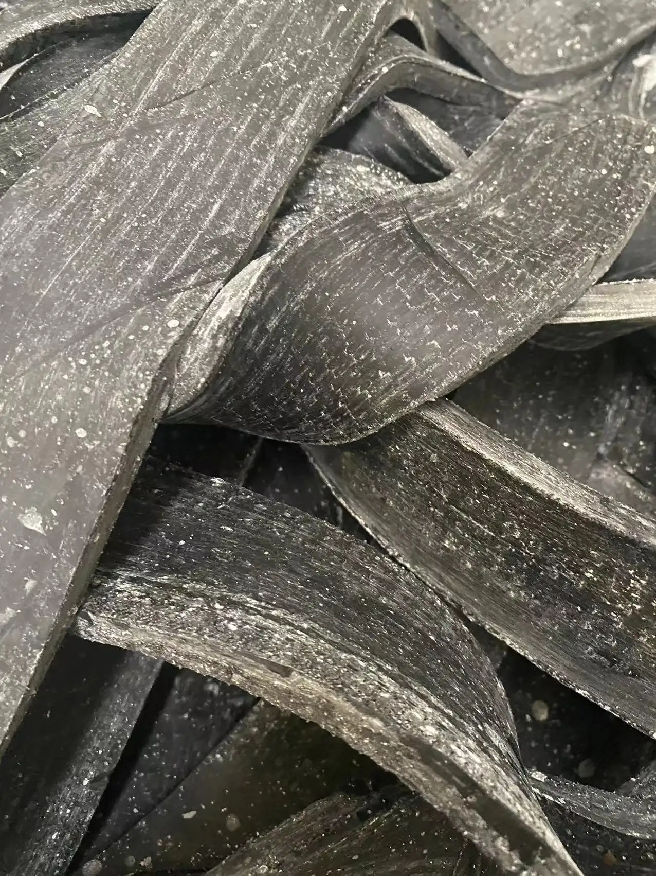 Close-up of overlapping black textured rubber or plastic strips with white speckles.