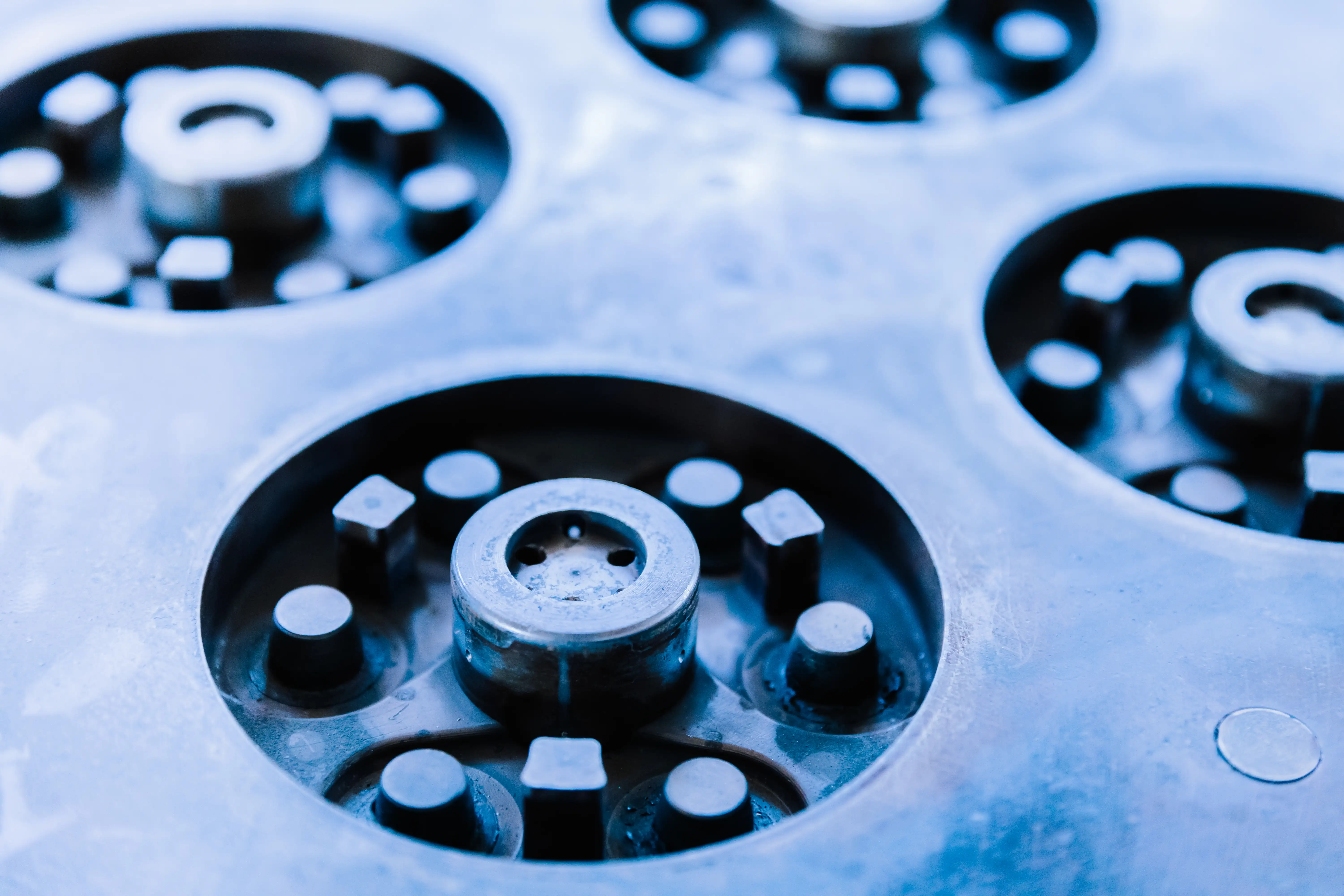 Close-up of circular metal mechanical parts with raised cylindrical and square features.