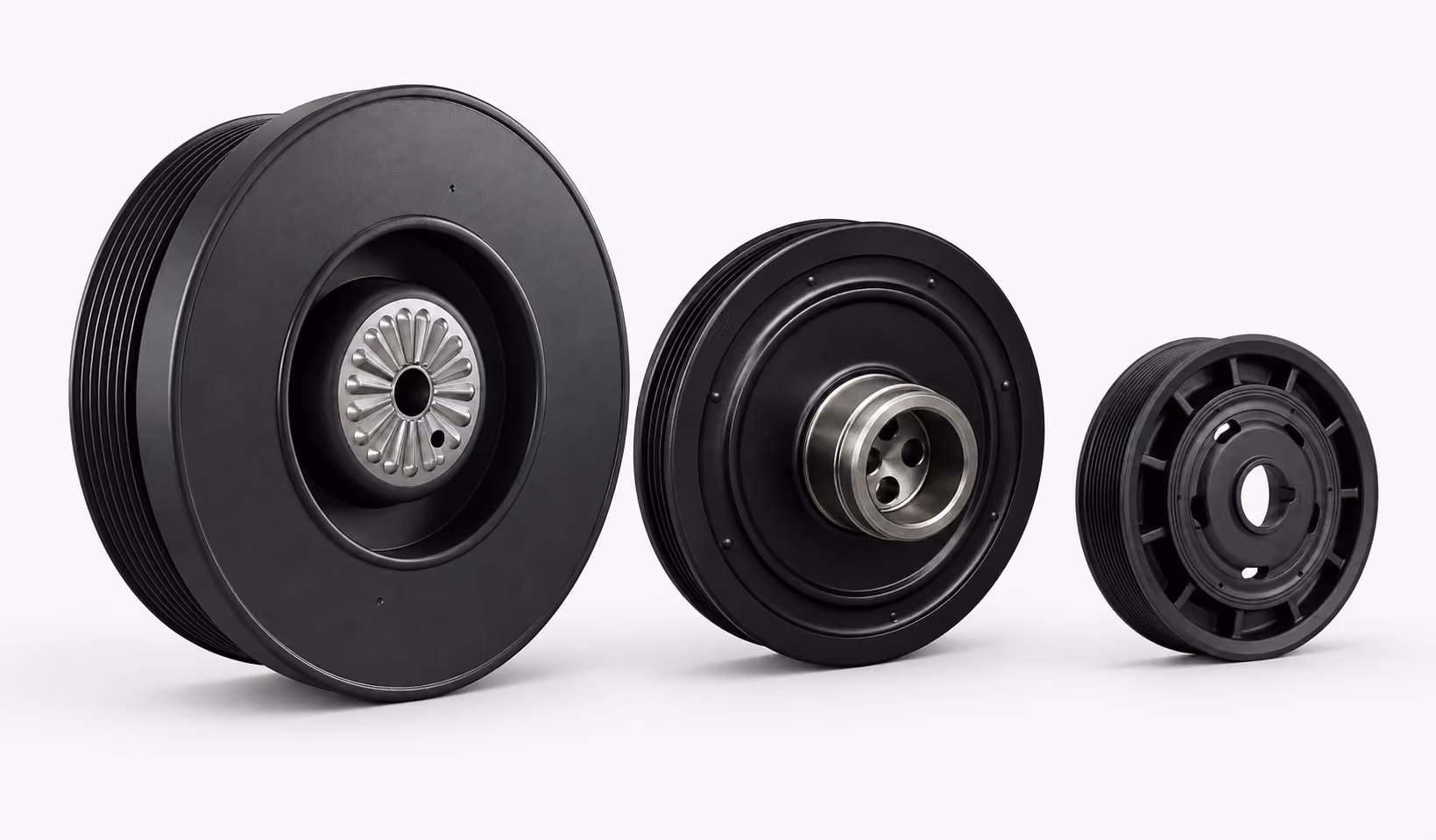 Three black mechanical pulleys with metal centers of varying sizes arranged from largest on the left to smallest on the right against a white background.