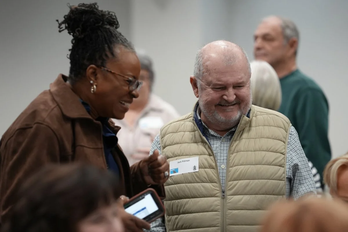 Two middle-aged church members smiling and engaging in conversation during fellowship.