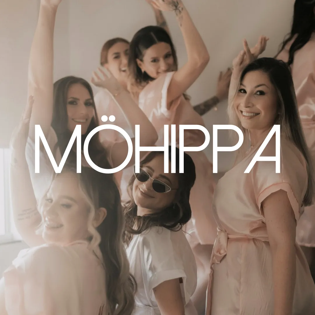 Glada kvinnor i rosa och vita klänningar firar tillsammans i ett ljust rum under en möhippa.