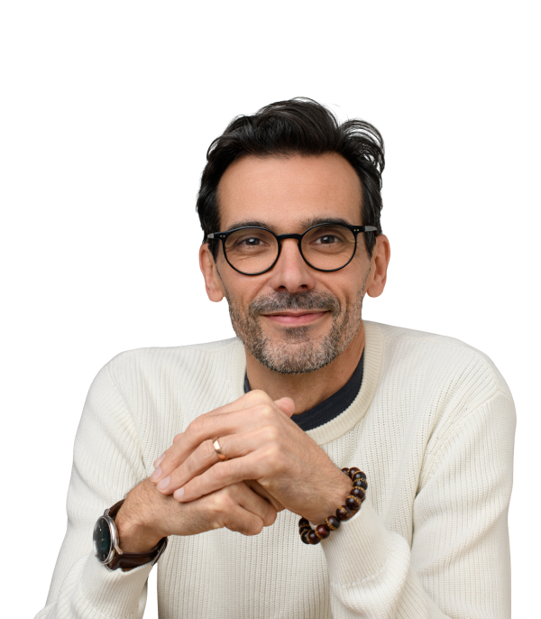 Portrait professionnel d’un créatif au regard confiant, lunettes rondes et style épuré, ambiance sobre et chaleureuse.