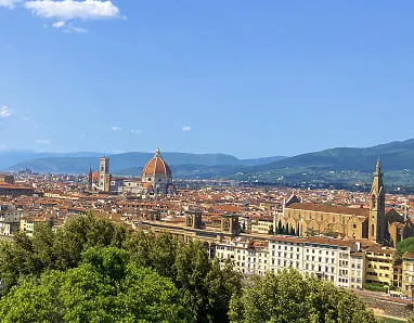 Panoramic view of Florence with the Florence Cathedral dome and city rooftops under a clear blue sky.