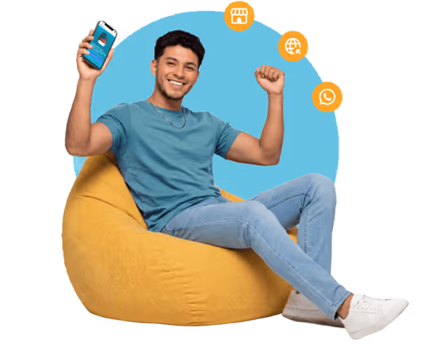 Hombre sonriente sentado en una puff amarilla sosteniendo un teléfono inteligente, con íconos naranjas que representan una tienda, un globo terráqueo y WhatsApp a su alrededor.