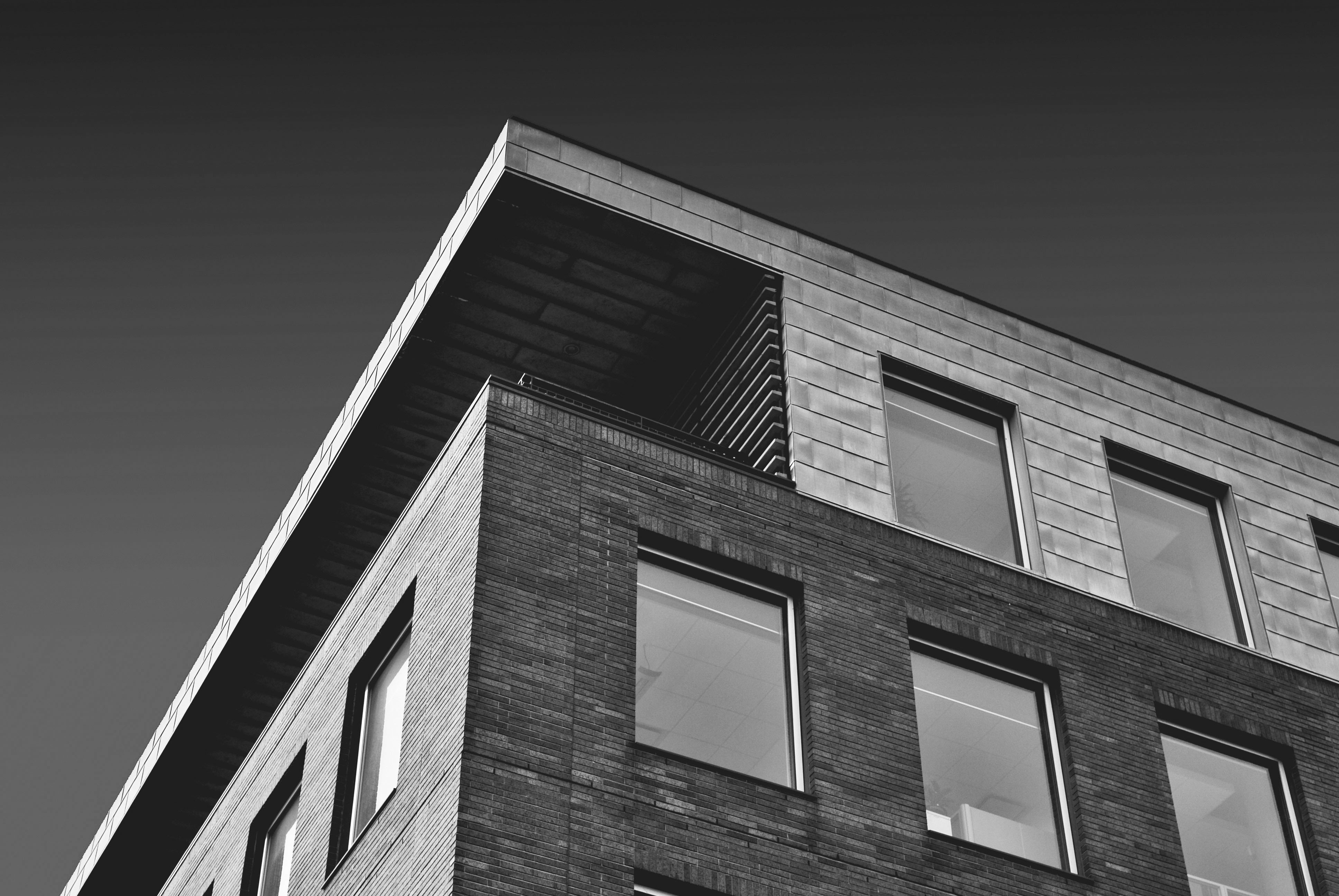Schwarz-weiß-Foto eines modernen Gebäudes mit einer Fassade aus Ziegeln und großen Fenstern unter einem klaren Himmel.
