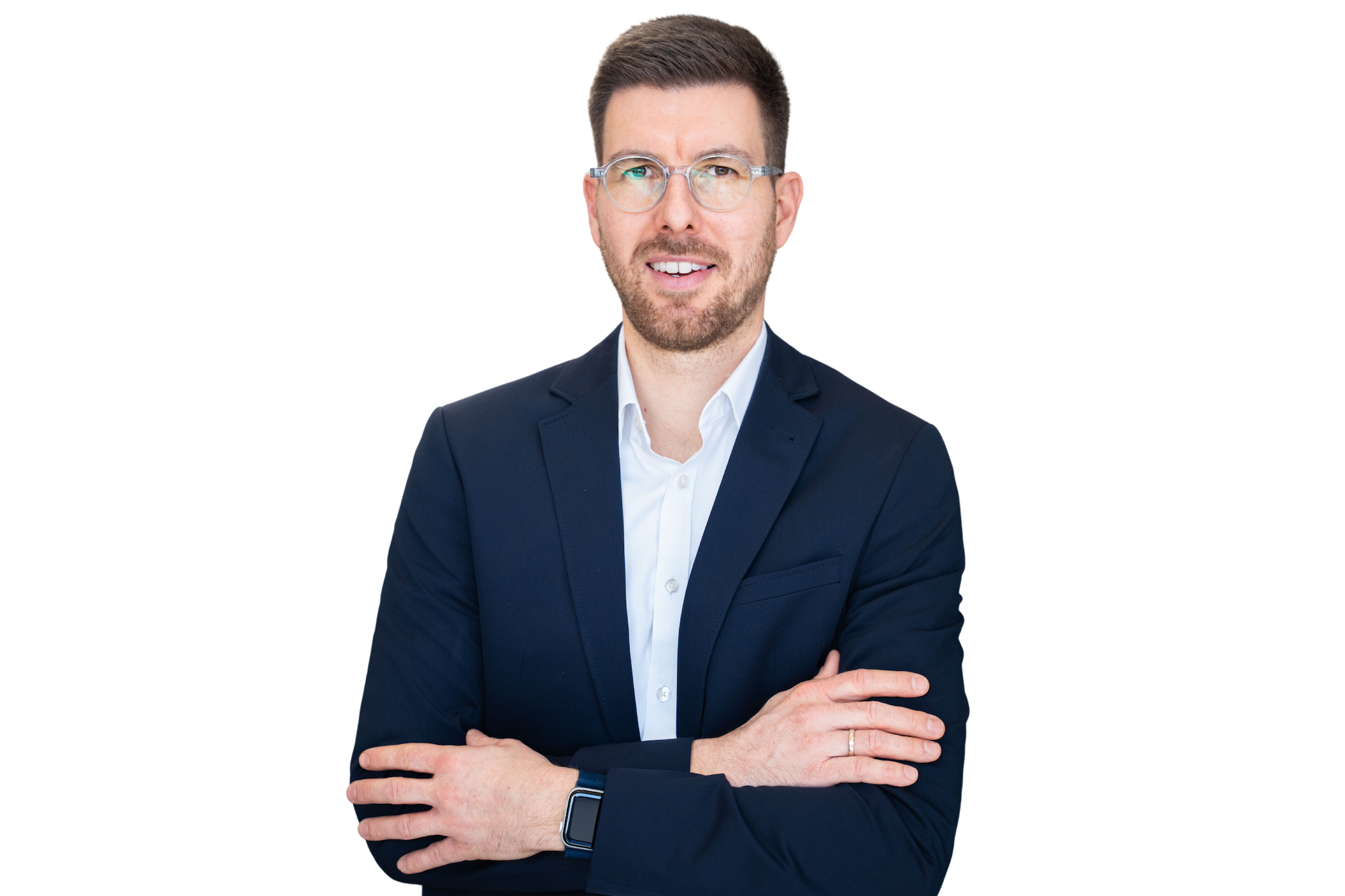 Mann mit klaren Brillen, blauem Anzug und weißem Hemd, der mit verschränkten Armen lächelt.