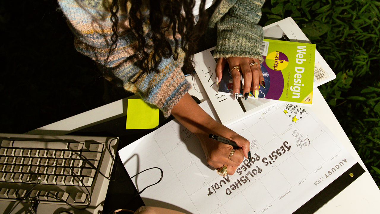 Hand with nail art writing Jessi's Polished Pages Audit on a desk calendar to schedule a website audit