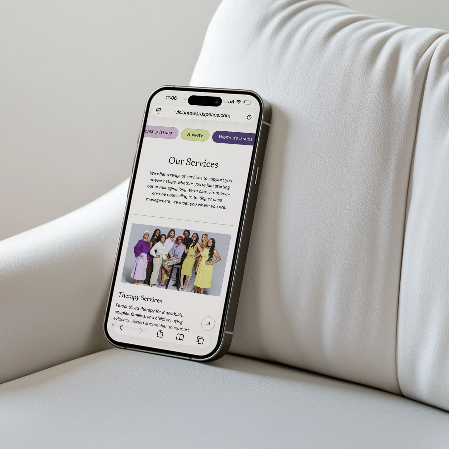 Vision Towards Peace mobile website design shown on a phone resting against a couch cushion, open to the Our Services section