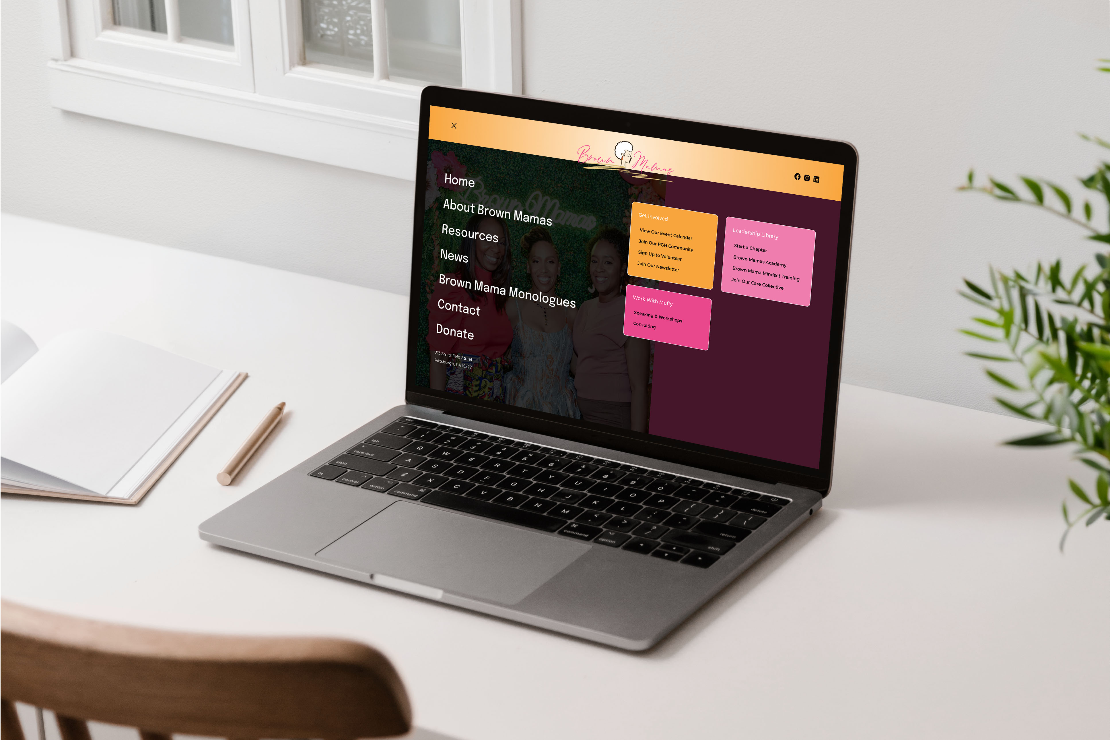 Brown Mamas full-screen navigation menu design shown on a laptop on a white desk, with large menu links and pink and orange link cards