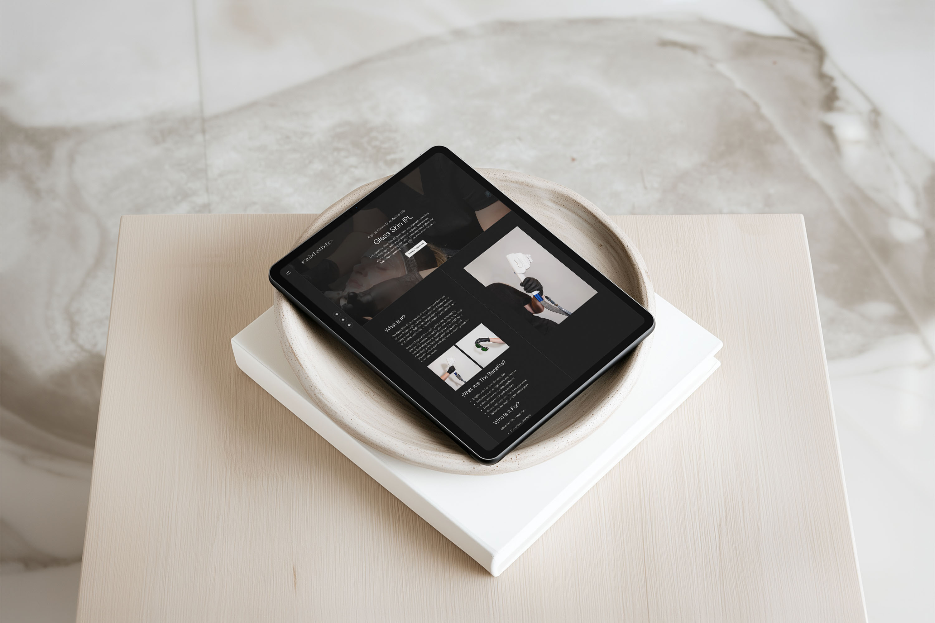 Scrubd Esthetics laser treatment page design shown on a tablet resting in a ceramic dish, with the headline "Glass Skin IPL."