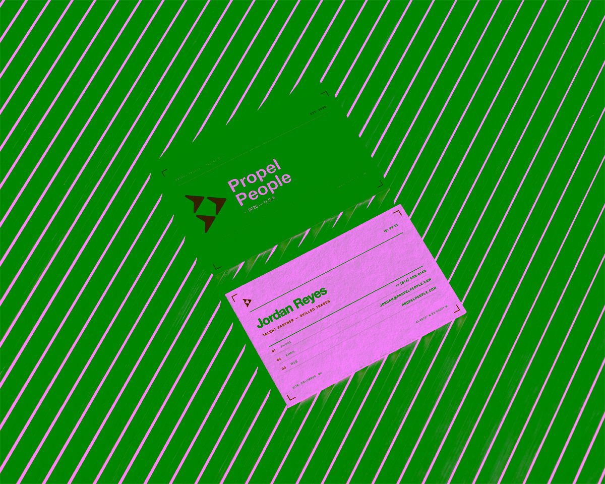 Two Propel business cards lie on a concrete surface showing either side of the card