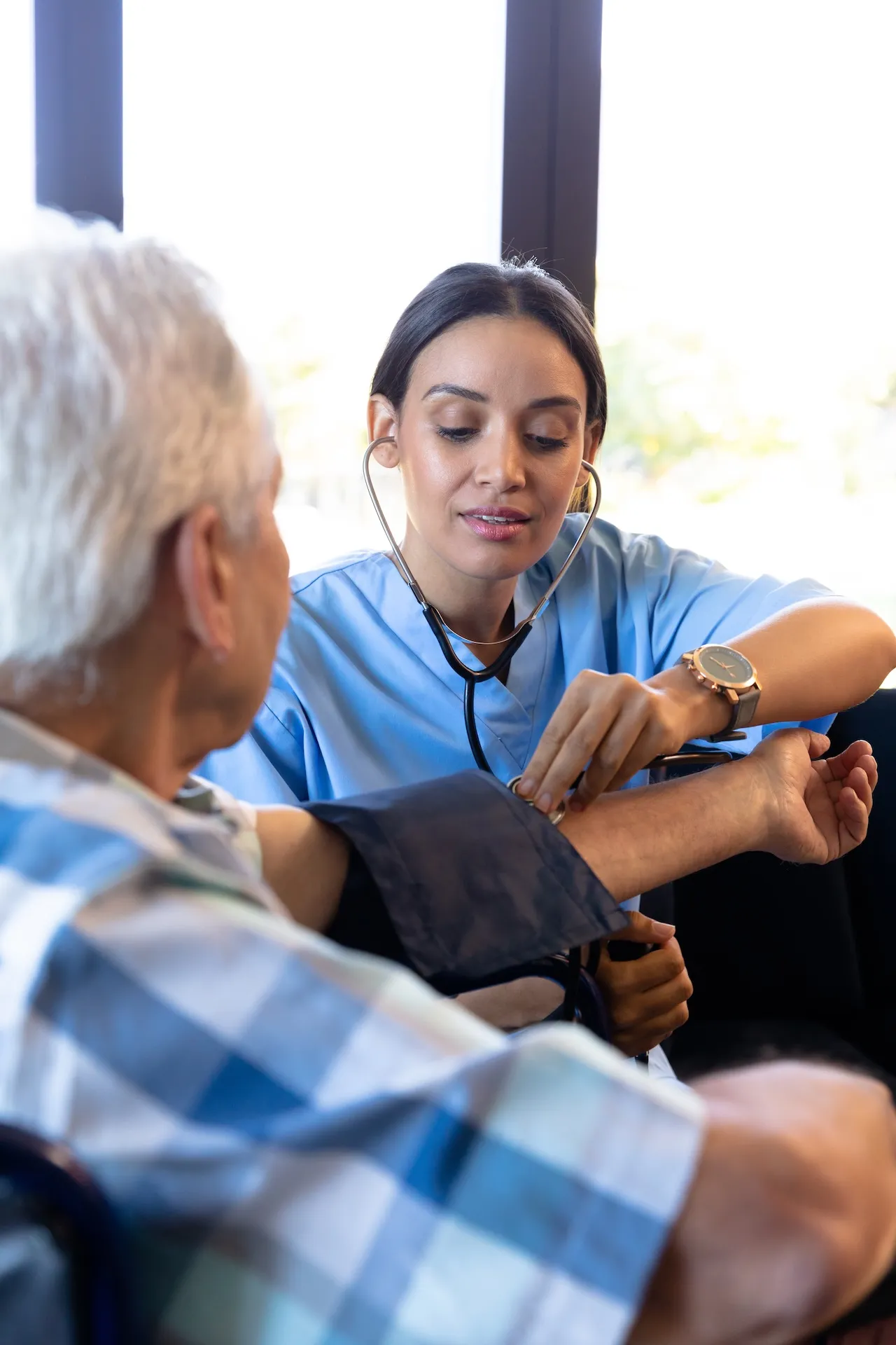 Doctor examining senior patient's arm with stethoscope during medical checkup