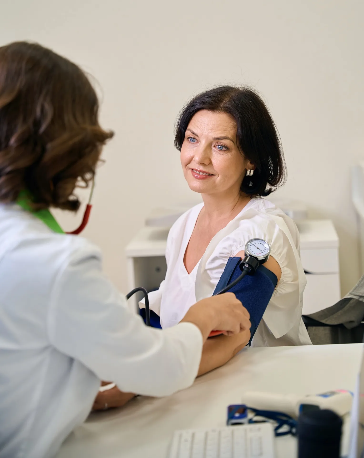 Doctor measuring patient's blood pressure with stethoscope and sphygmomanometer in medical clinic