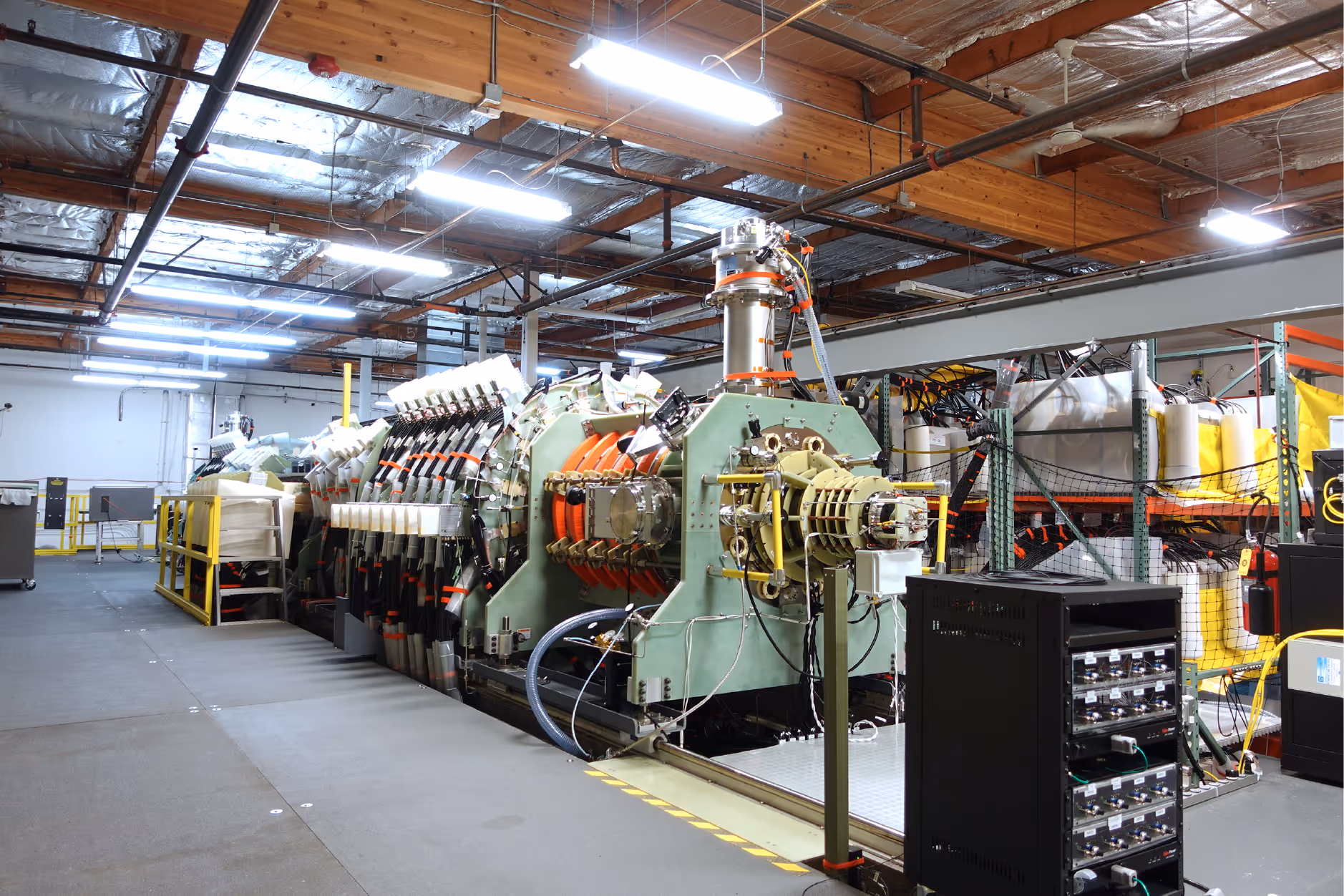 Large fusion machine with complex wiring and metal components in an industrial laboratory setting.