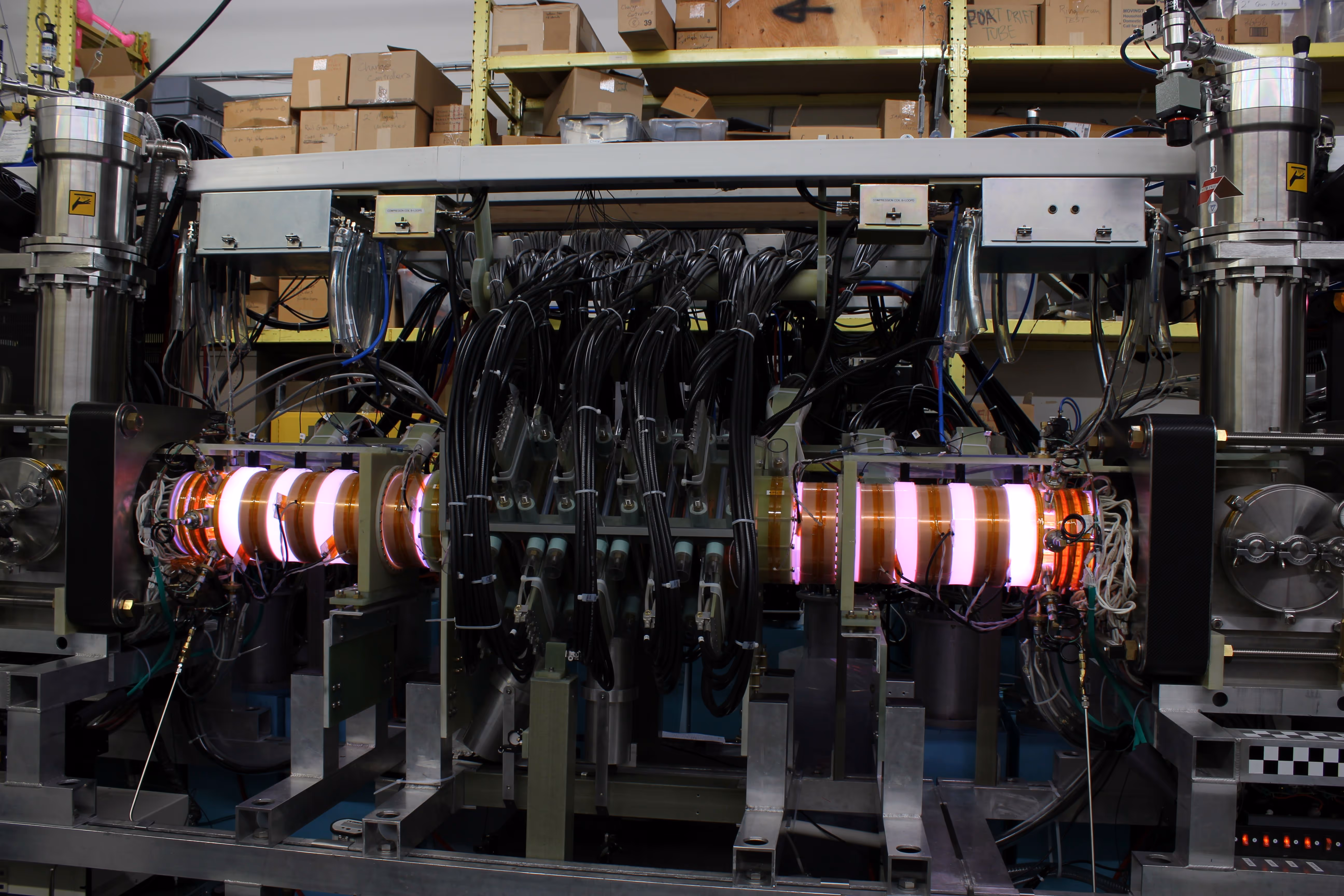 Laboratory equipment with glowing circular components and bundled black cables in an industrial setting.
