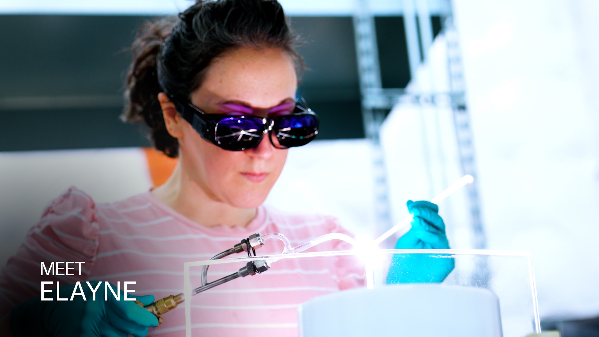Woman wearing protective glasses and gloves using a torch for glasswork in a workshop.