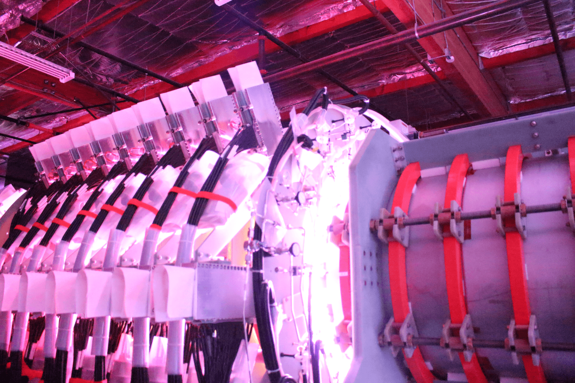 Close-up of Helion's Trenta fusion machine, a complex scientific machine with cables, metal components, and glowing purple light in a research facility.