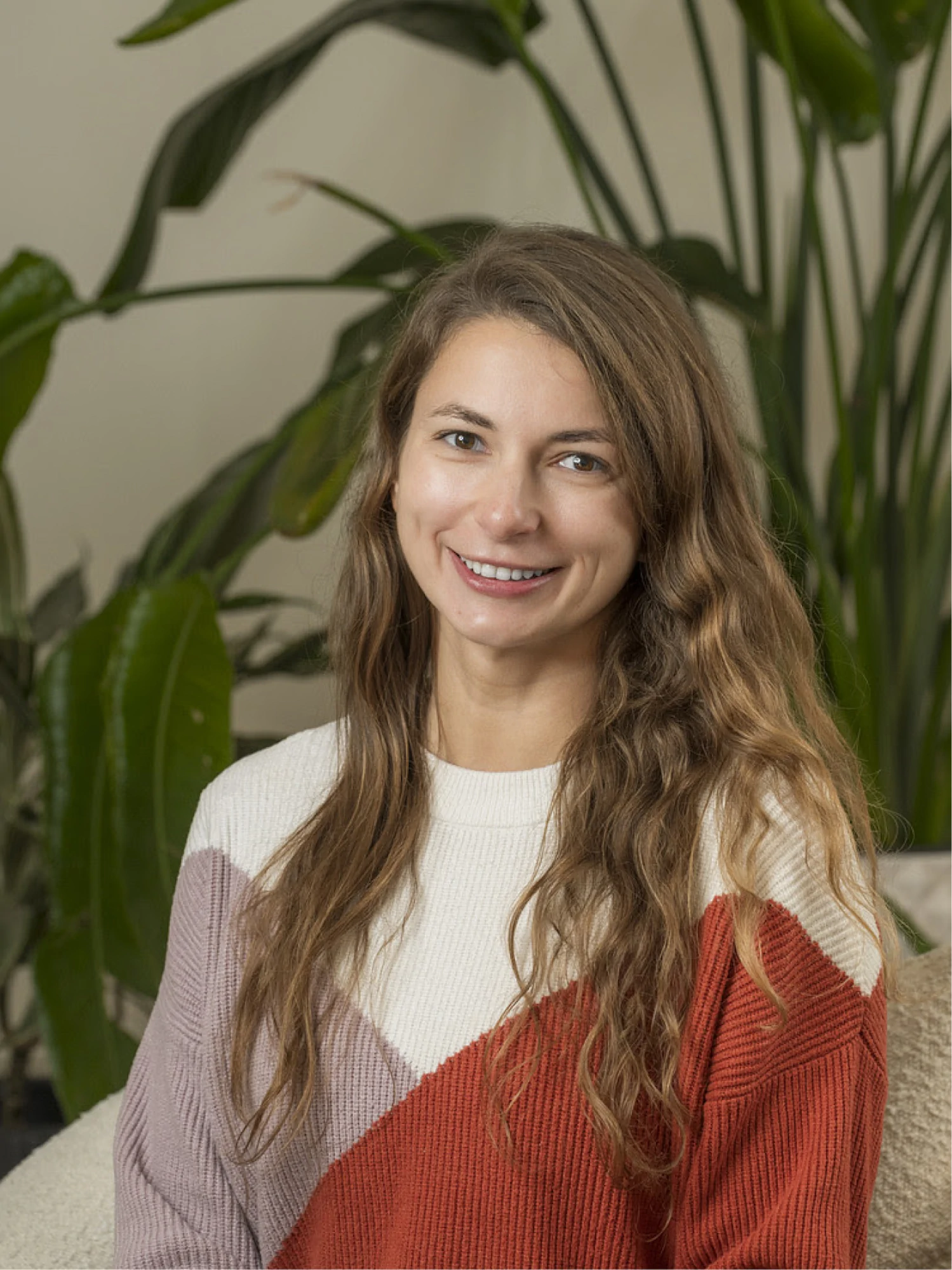 Team member headshot in front of a lush green plant