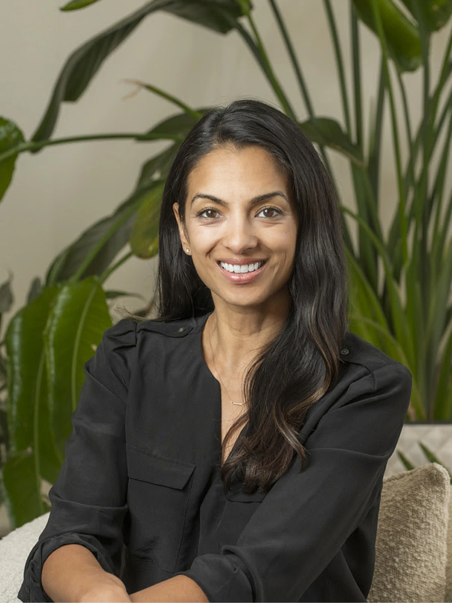 Team member headshot in front of a lush green plant