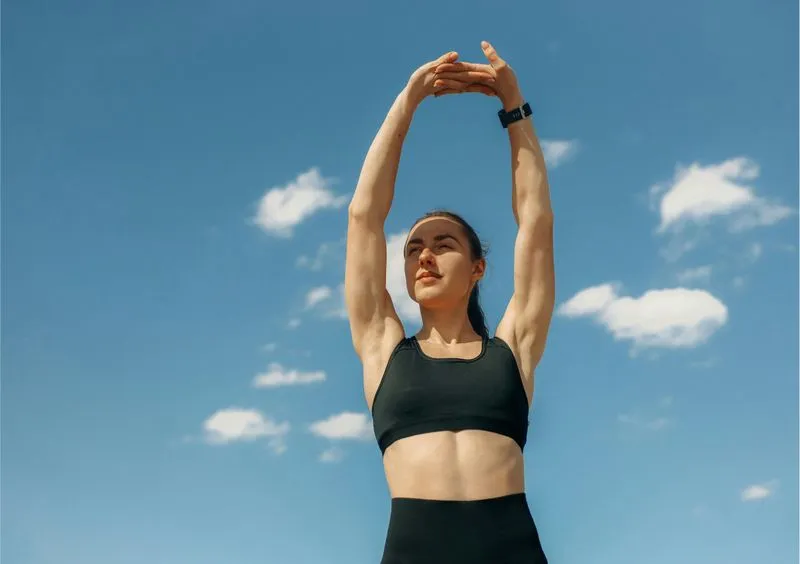 woman stretching with the sky and clouds behind her