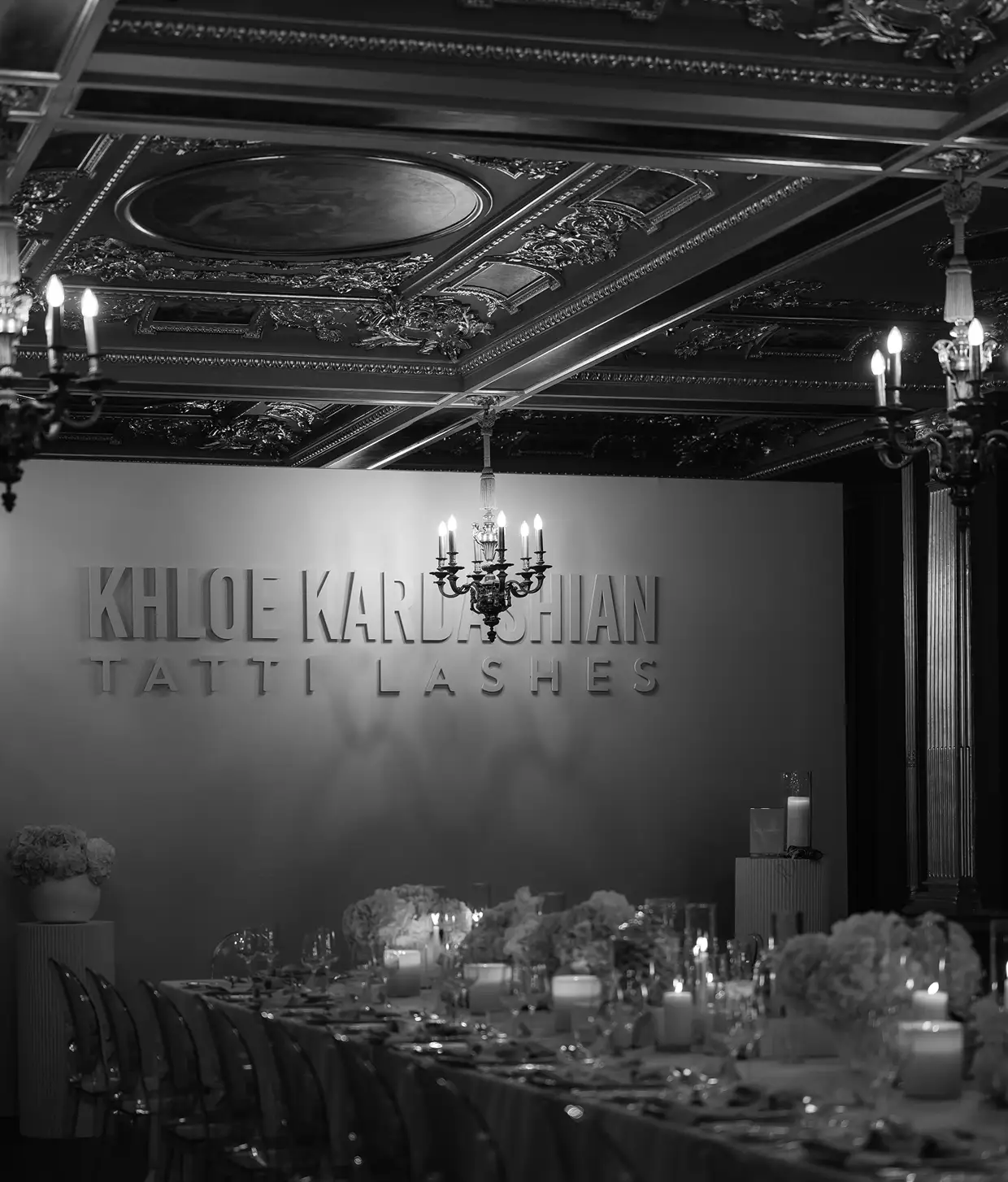 Elegant dining room with floral centerpieces and candles under ornate ceiling and chandeliers.