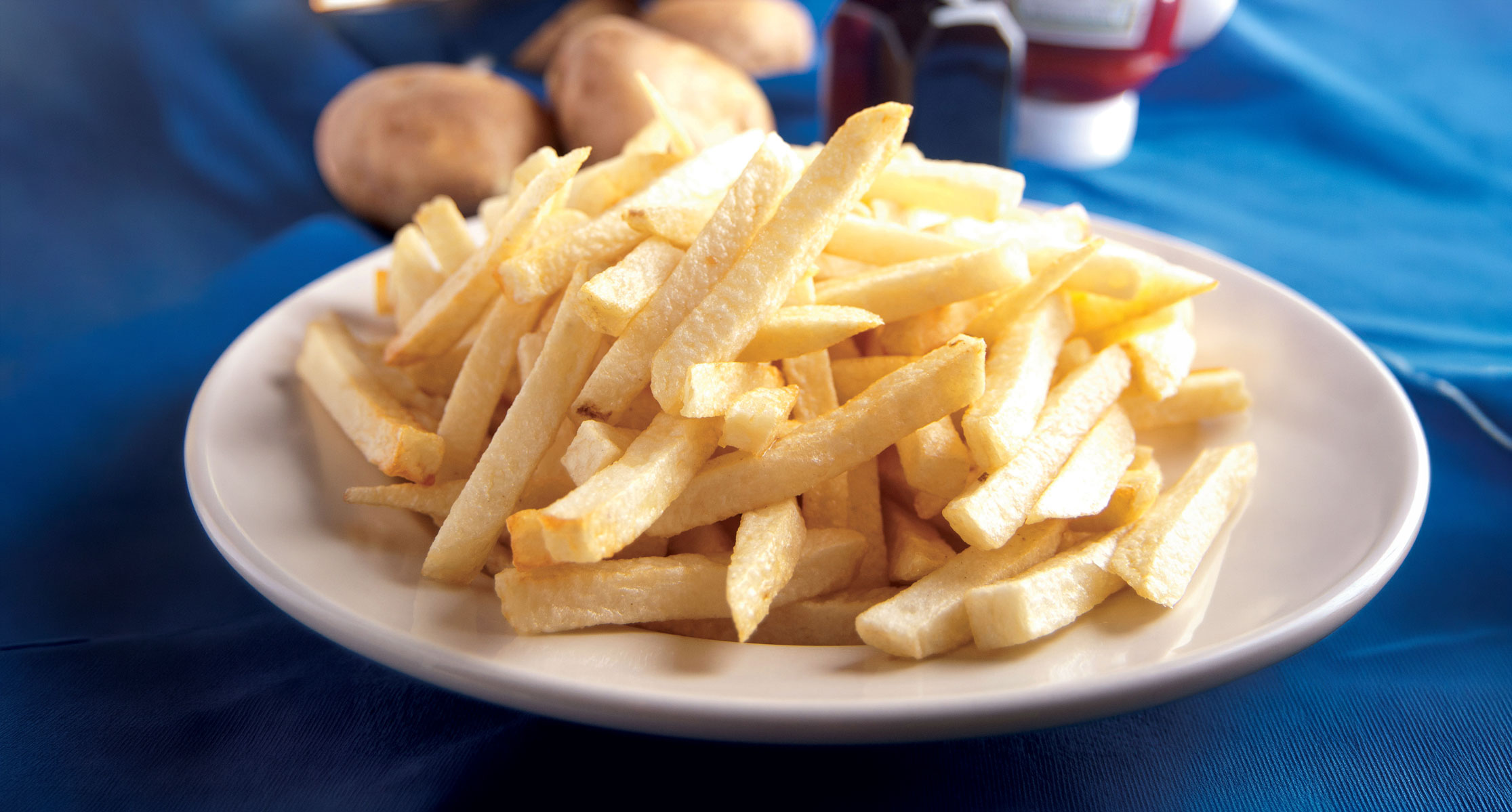 Plate of cheesesteak fries topped with melted cheese, sautéed onions, peppers, and thin slices of steak.