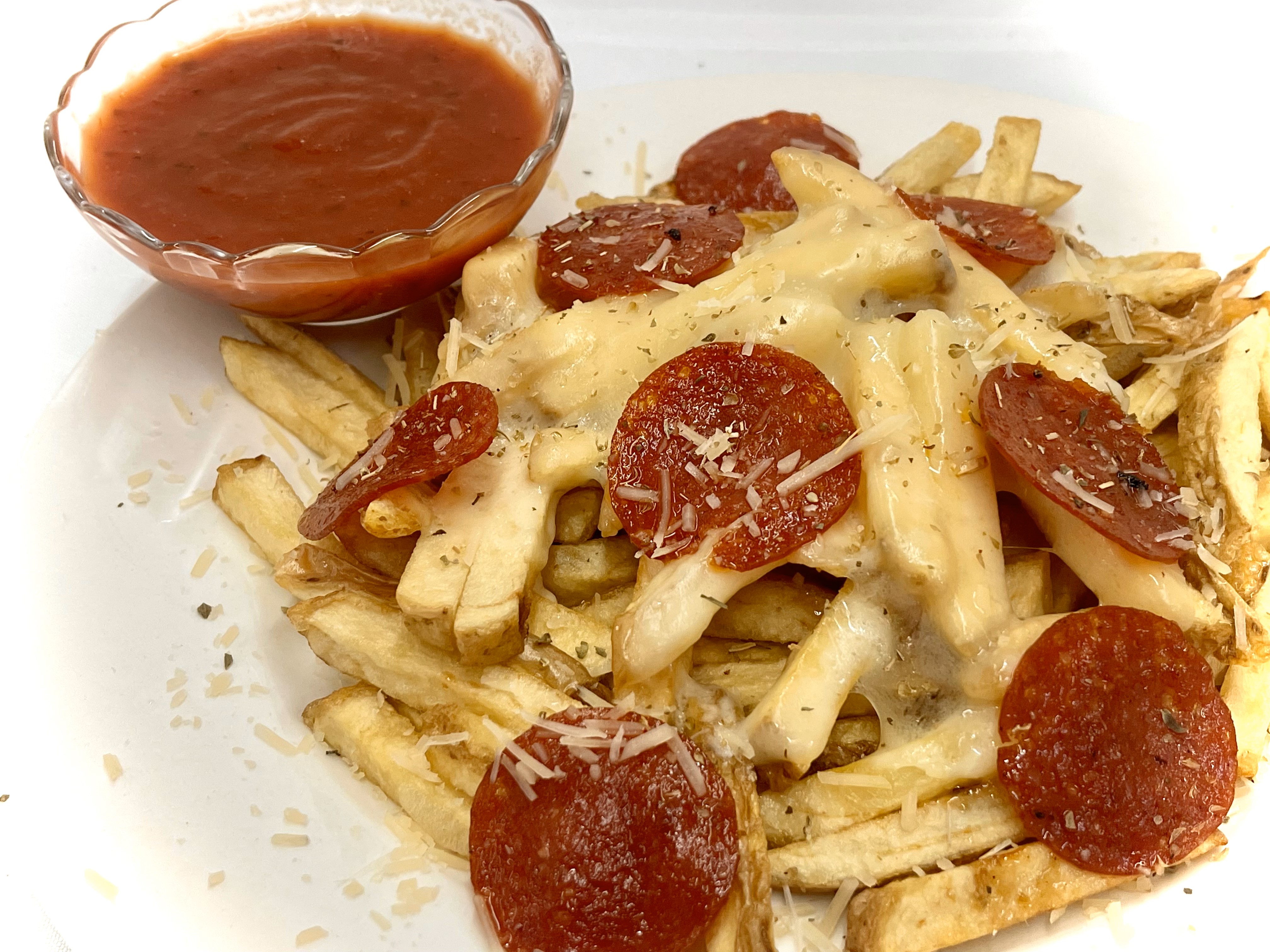Close-up of crinkle-cut fries topped with melted cheese, shredded BBQ pork, and drizzle of barbecue sauce.