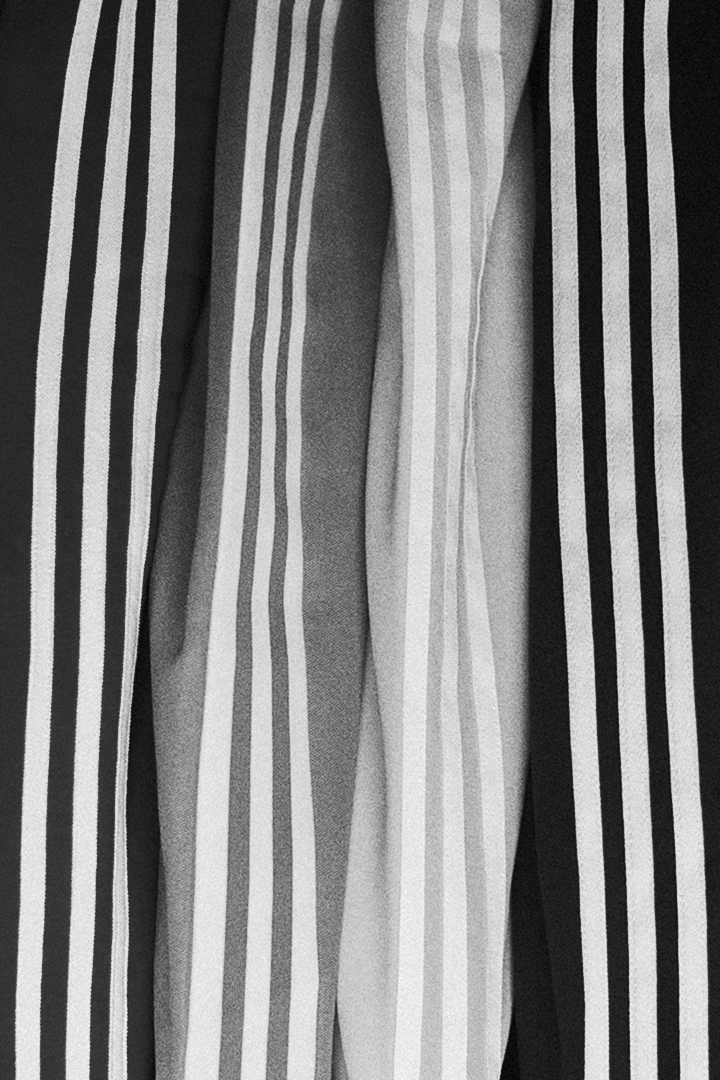 Close-up of fabric with vertical white stripes on black, gray, and white backgrounds.
