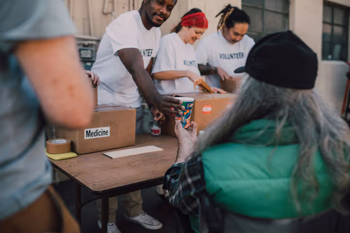 Volunteers distributing supplies and medicine to community members at an outdoor outreach event.