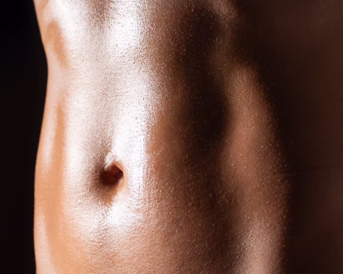 Primer plano del abdomen y la piel iluminados con luz cálida.