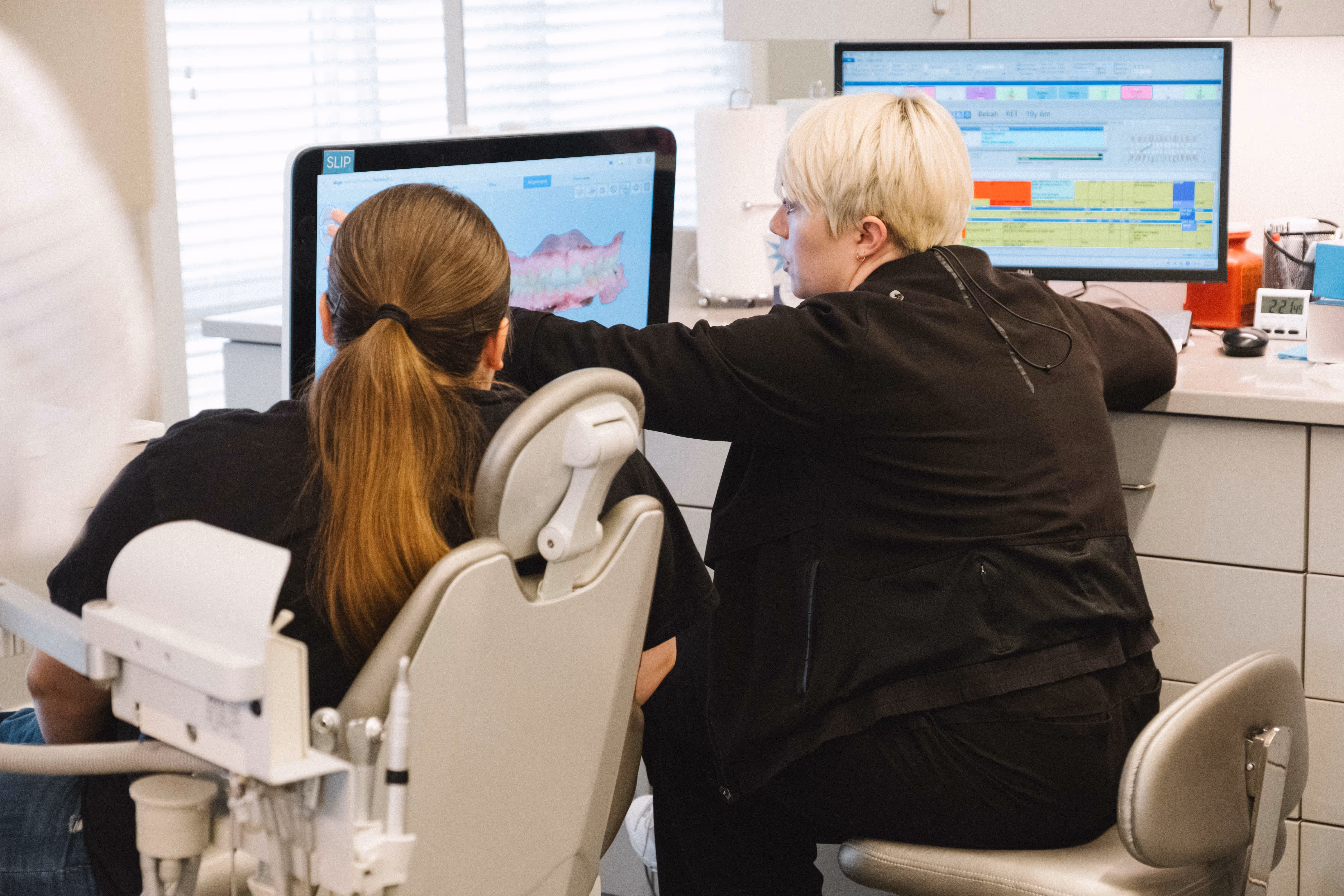 Dentist showing a patient a 3D dental scan on a computer in a dental office.