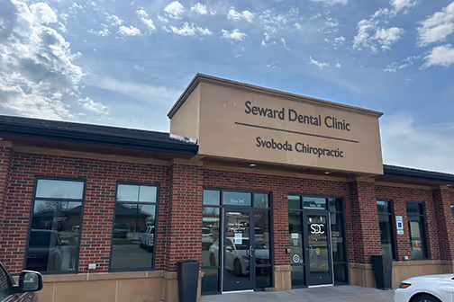Brick building with signage for Seward Dental Clinic and Svoboda Chiropractic under a partly cloudy sky.