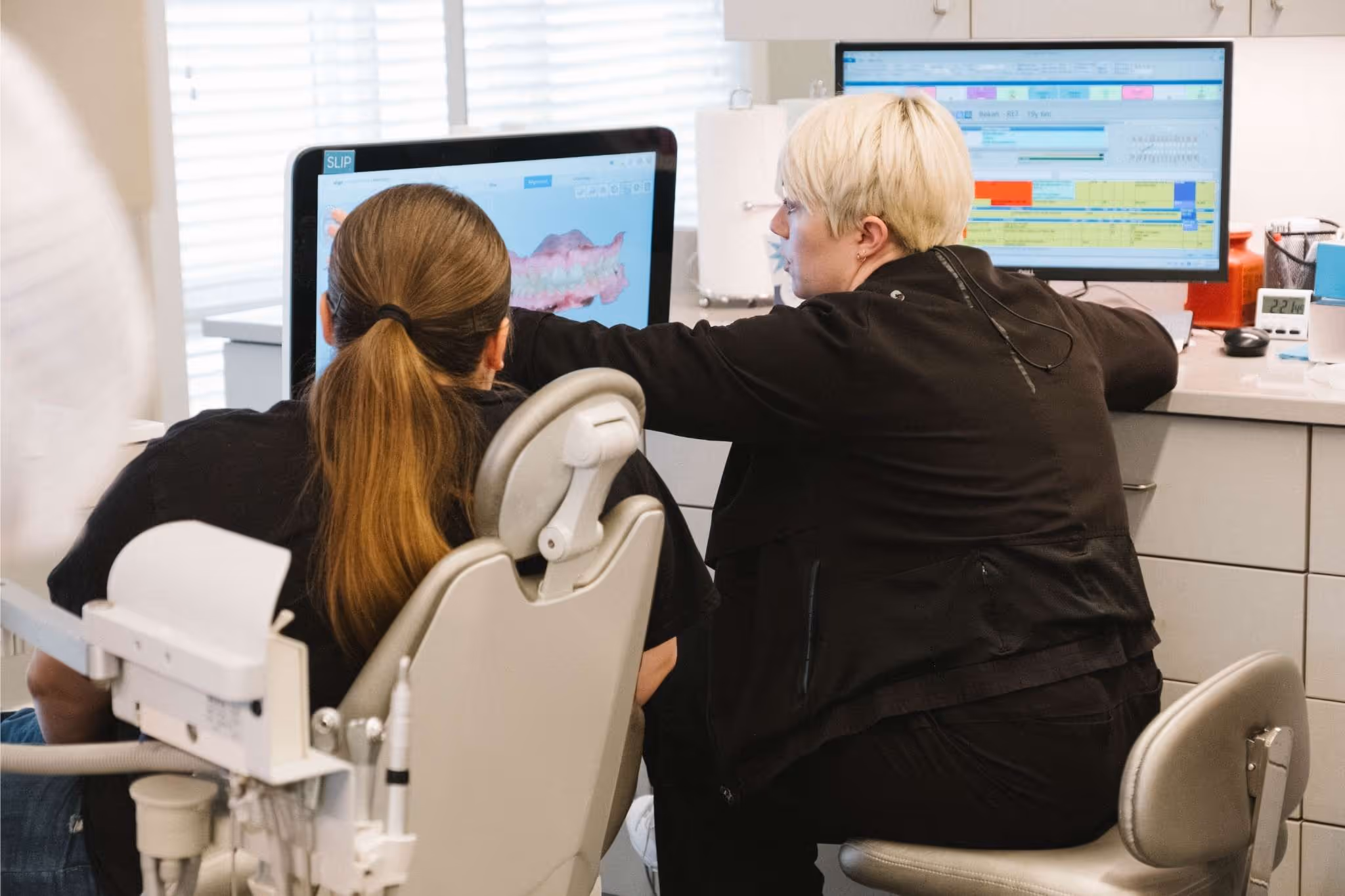 Dentist showing a patient a 3D dental scan on a computer in a dental office.
